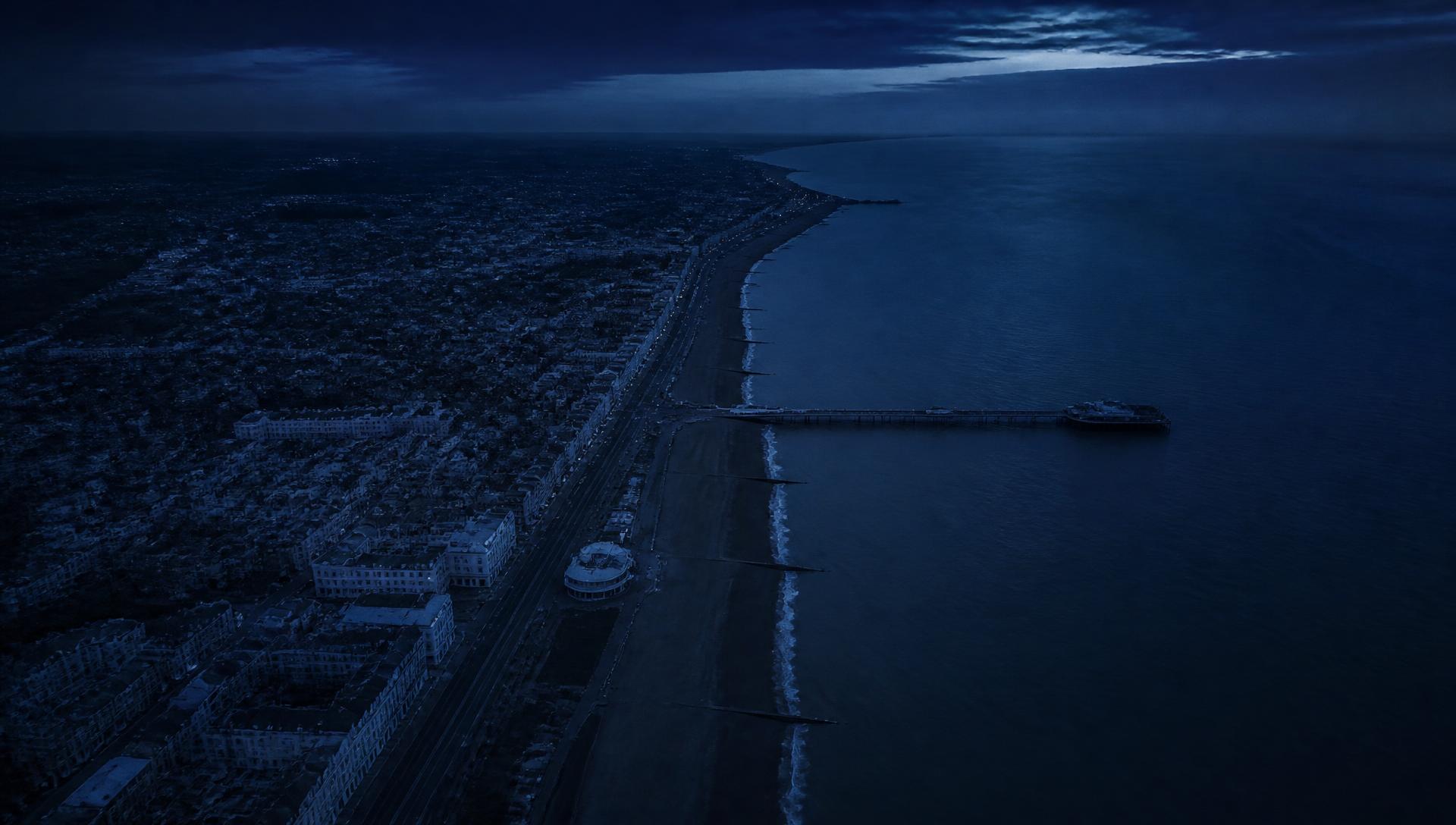Aerial view of the West Sussex coastline at dusk, looking along a seafront town towards the pier